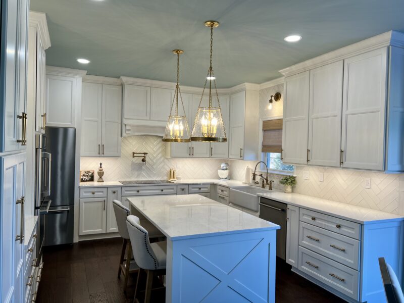 A stunning kitchen remodel featuring white cabinets, updated appliances, and pendant lights over a kitchen island.